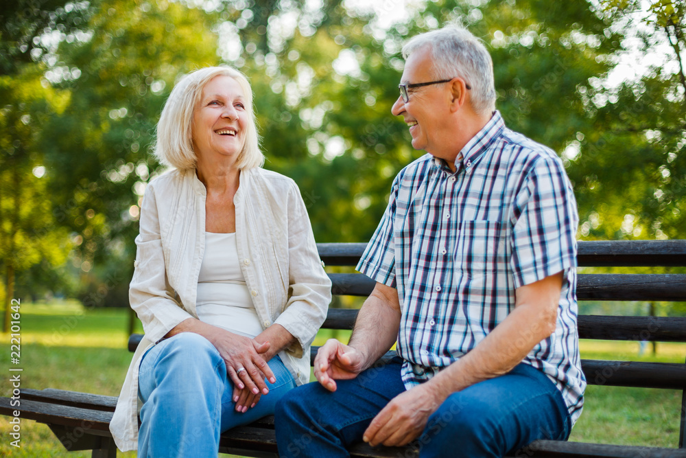Two happy seniors are sitting and talking in park. Two happy seniors are sitting and talking in park.