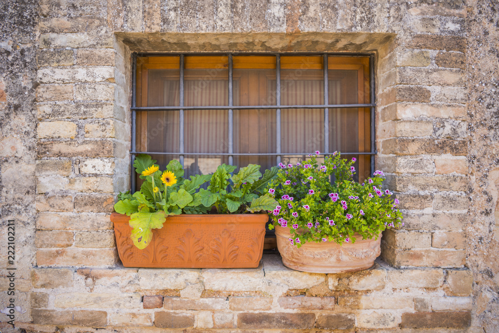 A window decorated with pots with flowers in a small Italian town. Spello, Umbria.