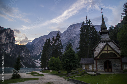 View of small chapel/church or Cappella Lago di Braies by tourist popular lake Lago di Braies (Pragser Wildsee) in summer. Dolomites mountains, Sudtirol, Italy
