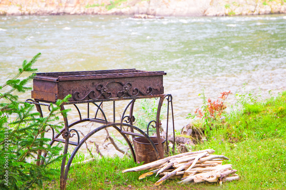 Barbeque brazier with firewood on BBQ outdoor party near the river.