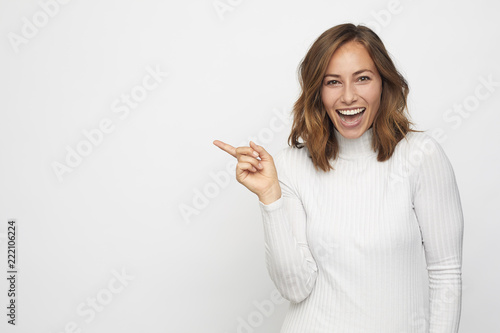 young woman pointing at copyspace looks in camera photo