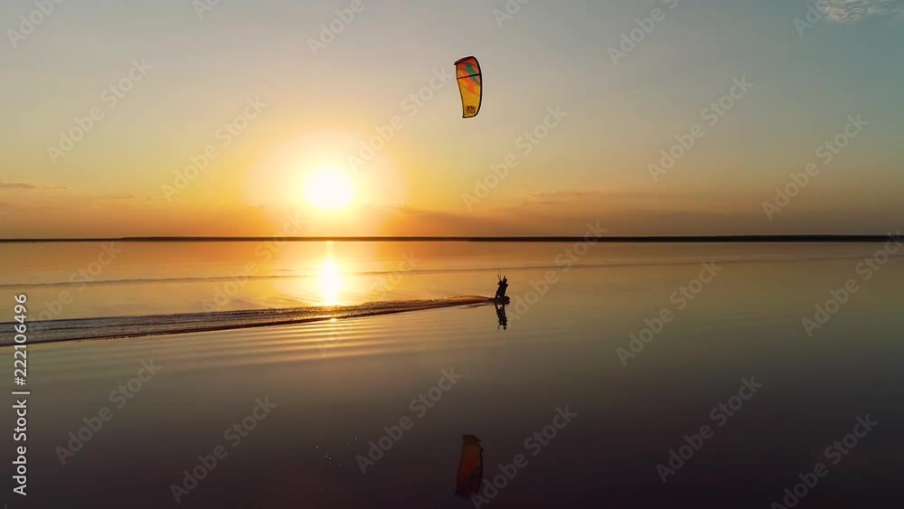 The shore of the lake in the distance, the sunset over the lake where a lonely man is engaged in kitesurfing The shore of the lake in the distance, the sunset over the lake where a lonely man is engaged in kitesurfing