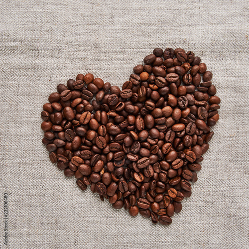 Heart from coffee beans on a beige fabric background. Flat lay, square crop.