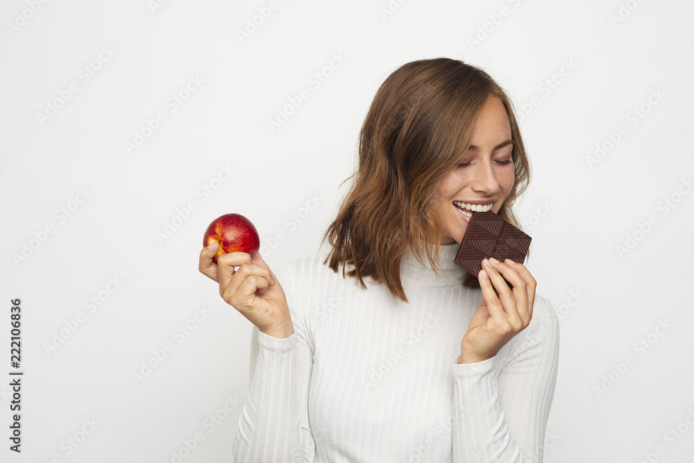 portrait of young woman with fruit and chocolate being tempted portrait of young woman with fruit and chocolate being tempted