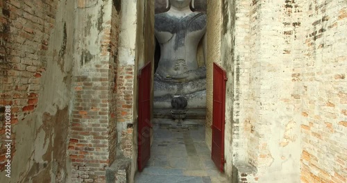 4K drone video footage gradually increasing altitude showing the big sitting Buddha statue at Wat Si Chum, a ruin site at Sukhothai Historical Park, a UNESCO world heritage site.