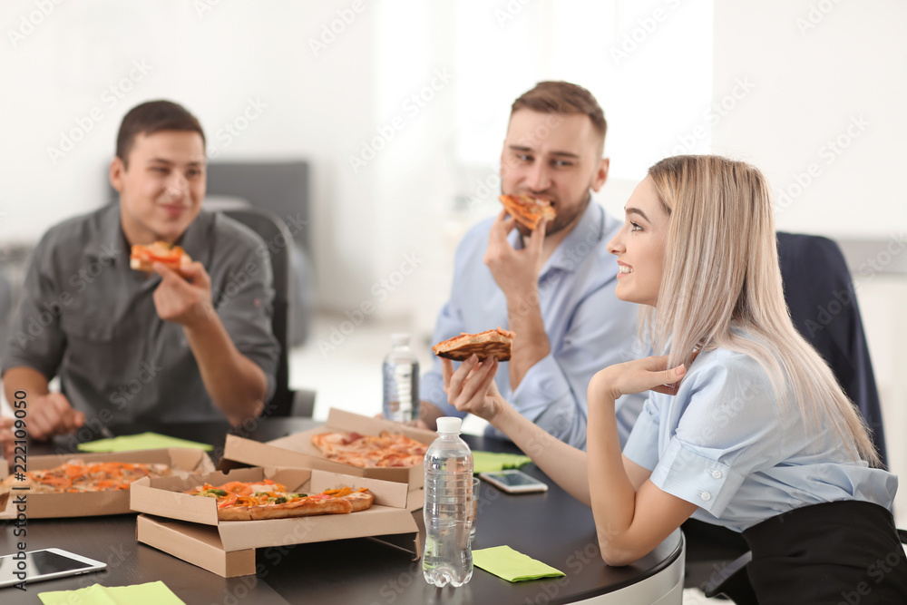 Young people eating pizza at table in office Young people eating pizza at table in office