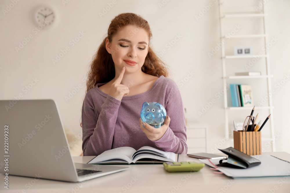 Young woman holding piggy bank indoors. Money savings concept Young woman holding piggy bank indoors. Money savings concept