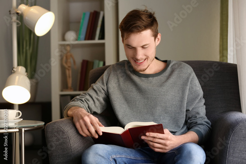 Young man reading book at home