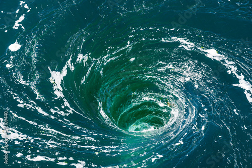 High angle view of a powerful whirlpool at the surface of green water with foam. photo