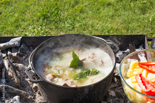 Shurpa soup in a large cast-iron cauldron outdoor. Summer food for hike.