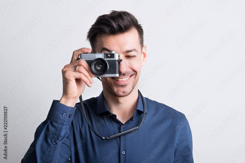 Portrait of a young man in a studio with a camera in front of his eye.