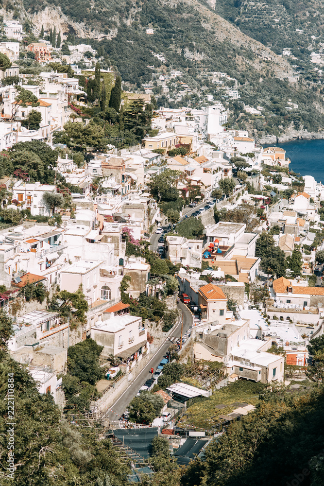 Fototapeta premium The coast of Positano, Amalfi in Italy. Panorama of the evening city and the streets with shops and cafes. Houses by the sea and the beach. Ancient architecture and temples