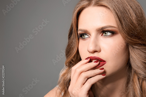 Fashionable young woman with beautiful manicure on grey background