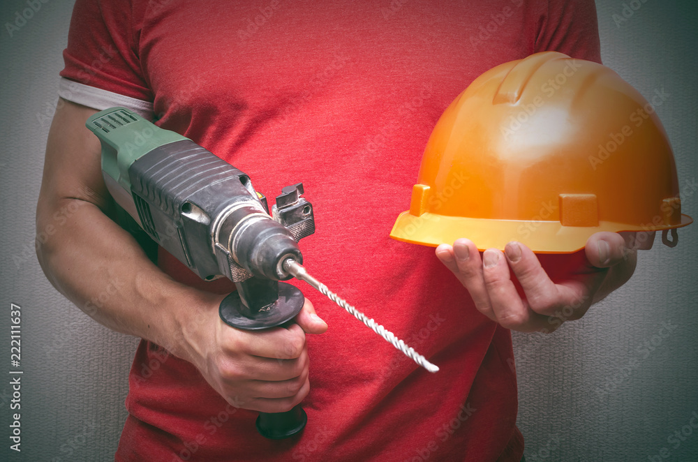 Builder worker with drill perforator in hands. Under construction concept background.