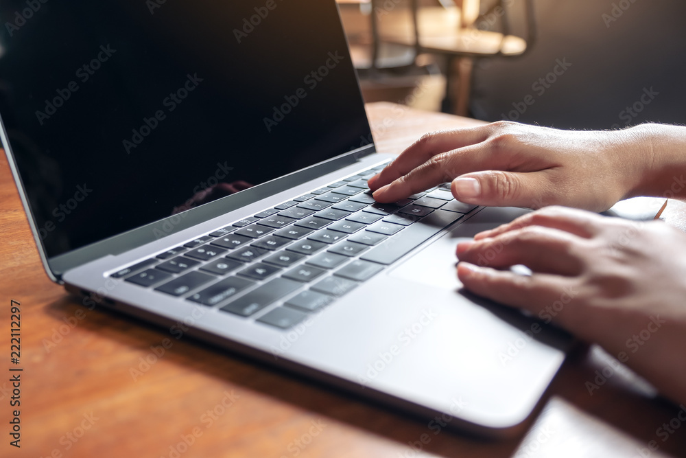 Closeup image of hands using and typing on laptop keyboard on wooden table Closeup image of hands using and typing on laptop keyboard on wooden table