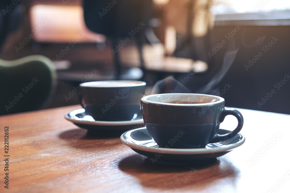 Closeup image of two blue cups of hot  coffee on vintage wooden table in cafe