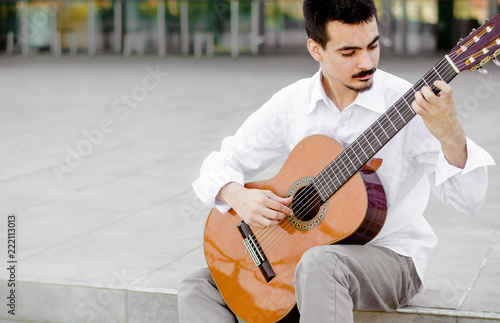 Young professional guitarist playing outside photo