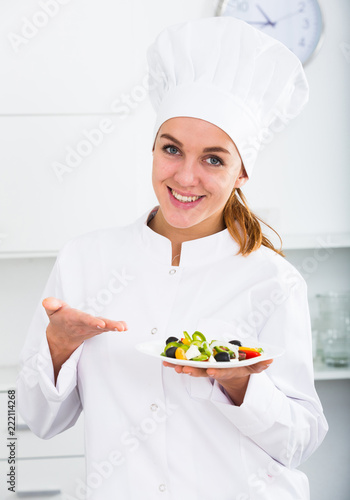 portrait of young coosie woman showing salad at kitchen photo