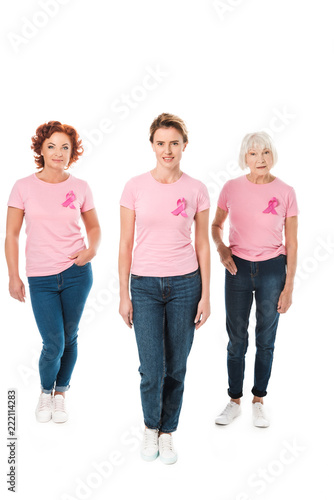 women in pink t-shirts with breast cancer awareness ribbons looking at camera isolated on white