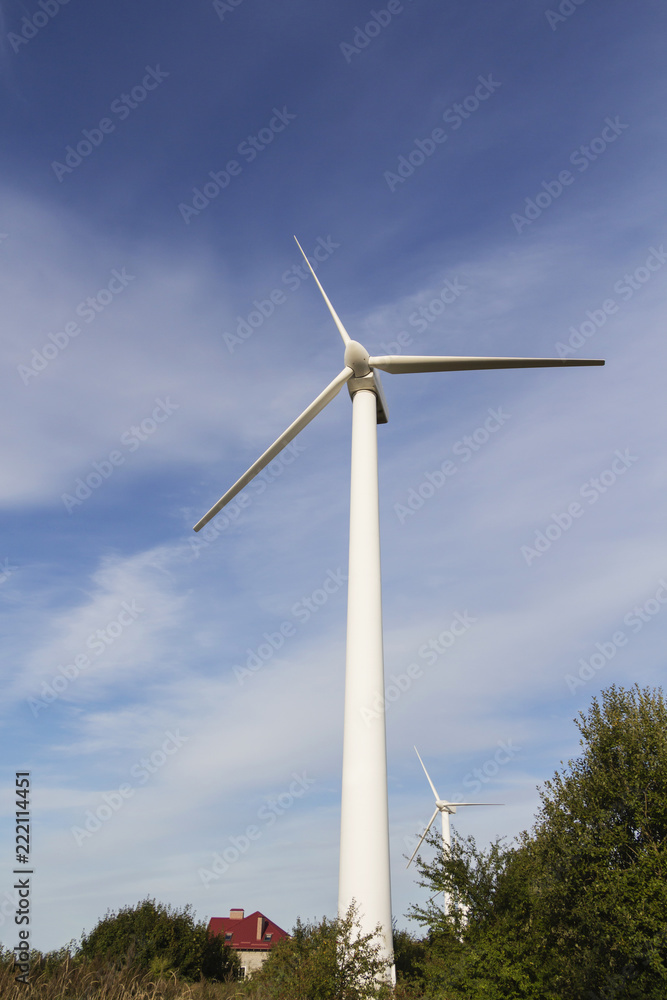 Windmill for electricity among the trees with the house. Windmill for electricity among the trees with the house.