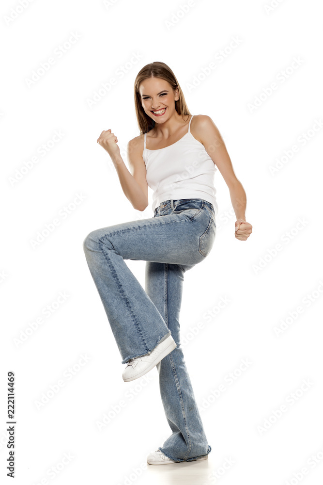 Happy young pretty woman posing in bell bottom jeans on white background Happy young pretty woman posing in bell bottom jeans on white background