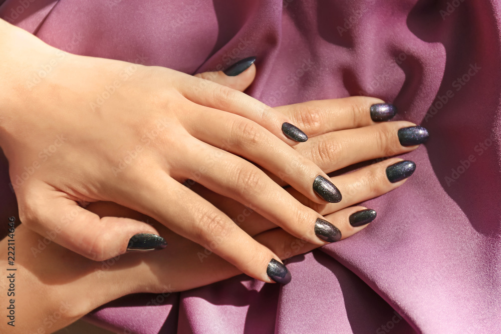 Hands of young woman with stylish manicure on cloth, closeup