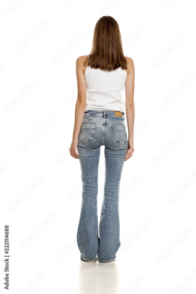 Obraz premium Back view of young pretty woman posing in bell bottom jeans on white background