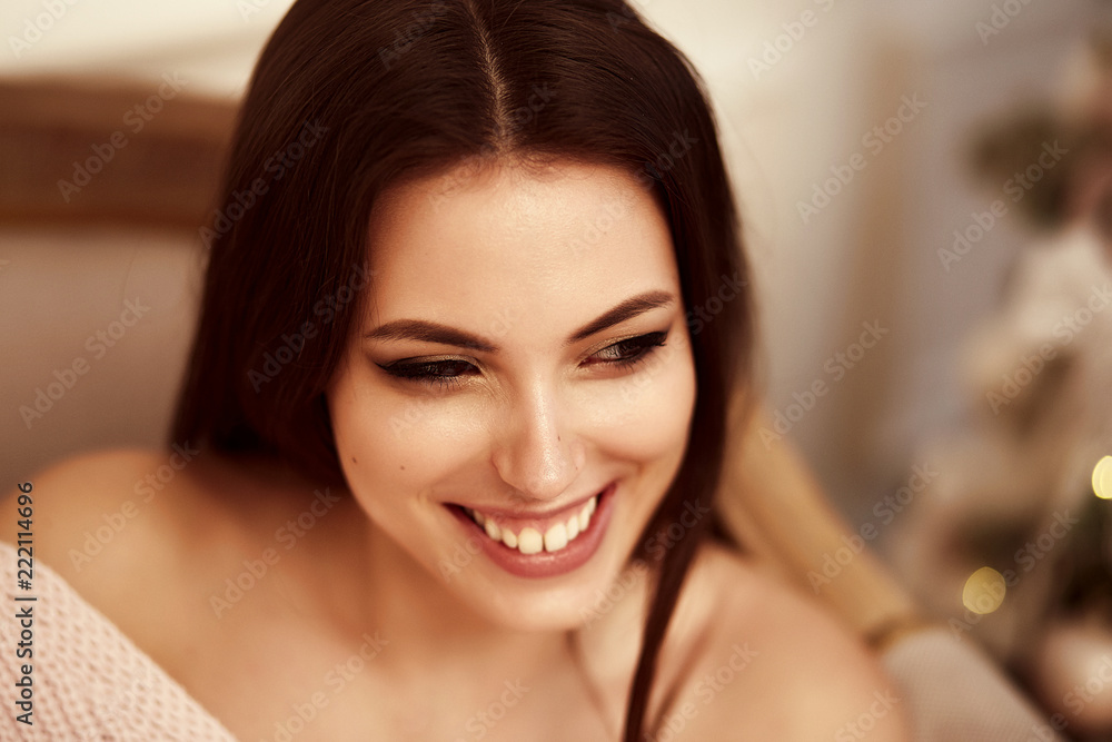 Beautiful woman sitting in the Christmas decorations in a sweater and smiling Beautiful woman sitting in the Christmas decorations in a sweater and smiling