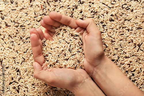 Female hands with heap of long grain rice, top view