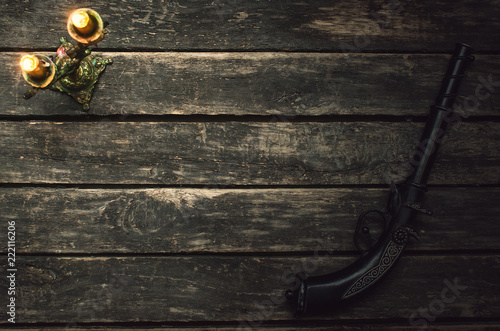 Musket gun and burning candle on wooden table background with copy space. photo