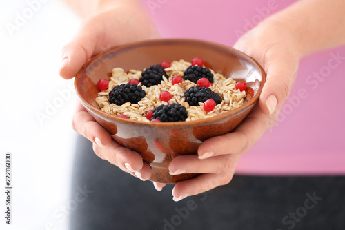 Woman with bowl of tasty oatmeal, closeup