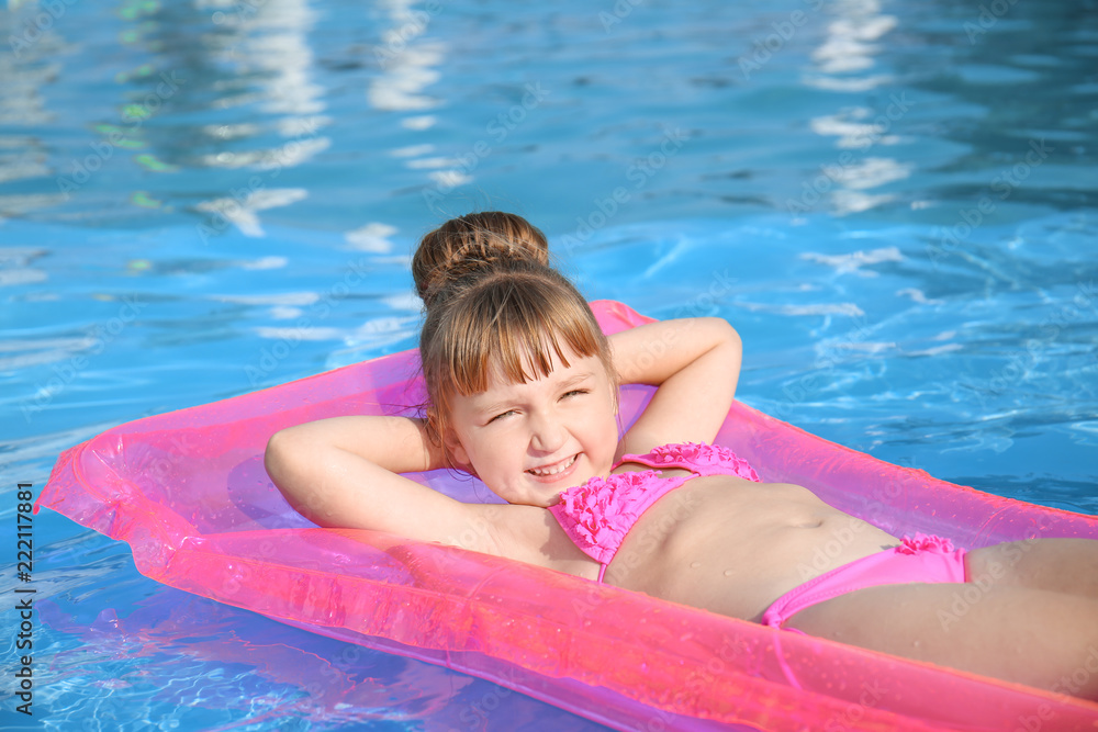 Cute little girl resting on inflatable mattress in swimming pool