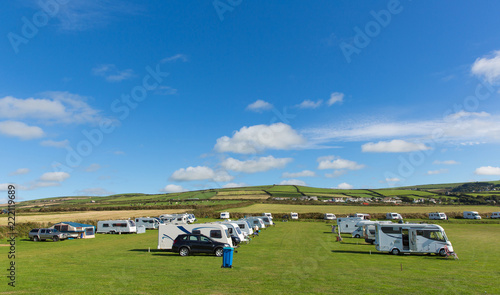 Motorhomes and campervans parked on a camping site in beautiful field in summer with blue sky