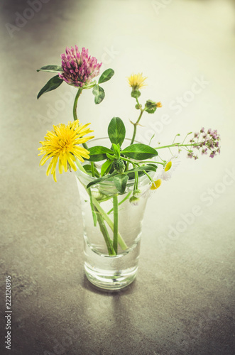 Fototapeta Naklejka Na Ścianę i Meble -  A small bouquet of wildflowers in a glass. Vintage toned image.