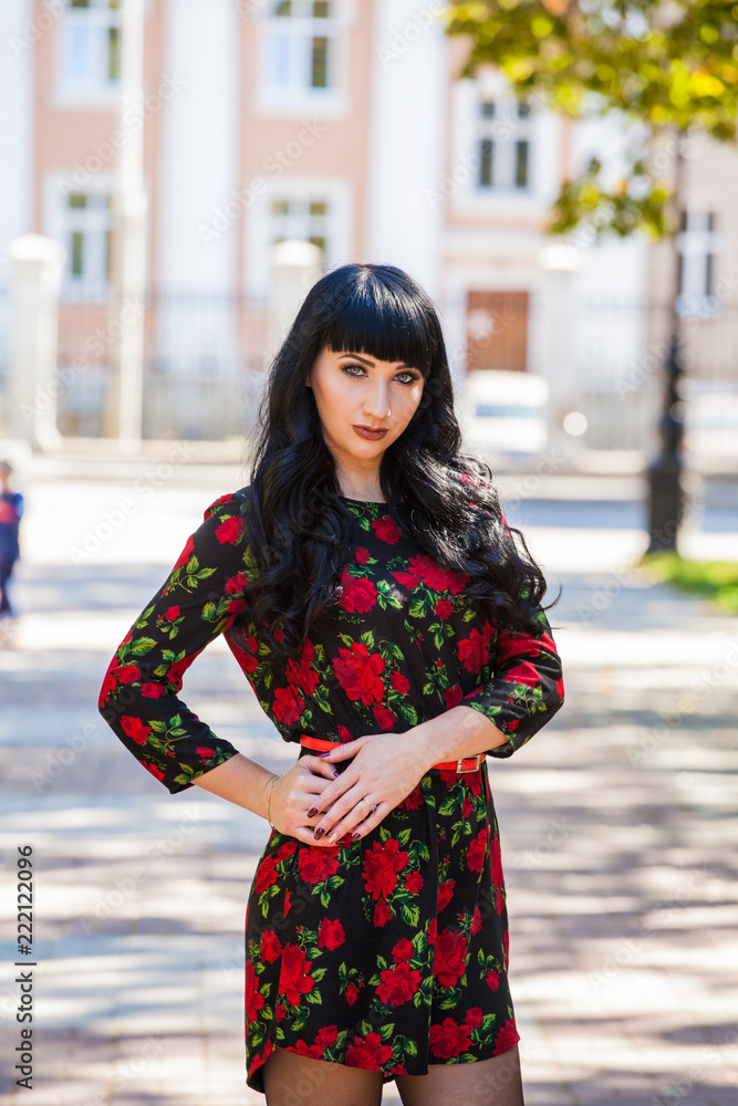 beautiful girl in an effet dress with flowers for a walk in the city. Sexy brunette on a historic building background