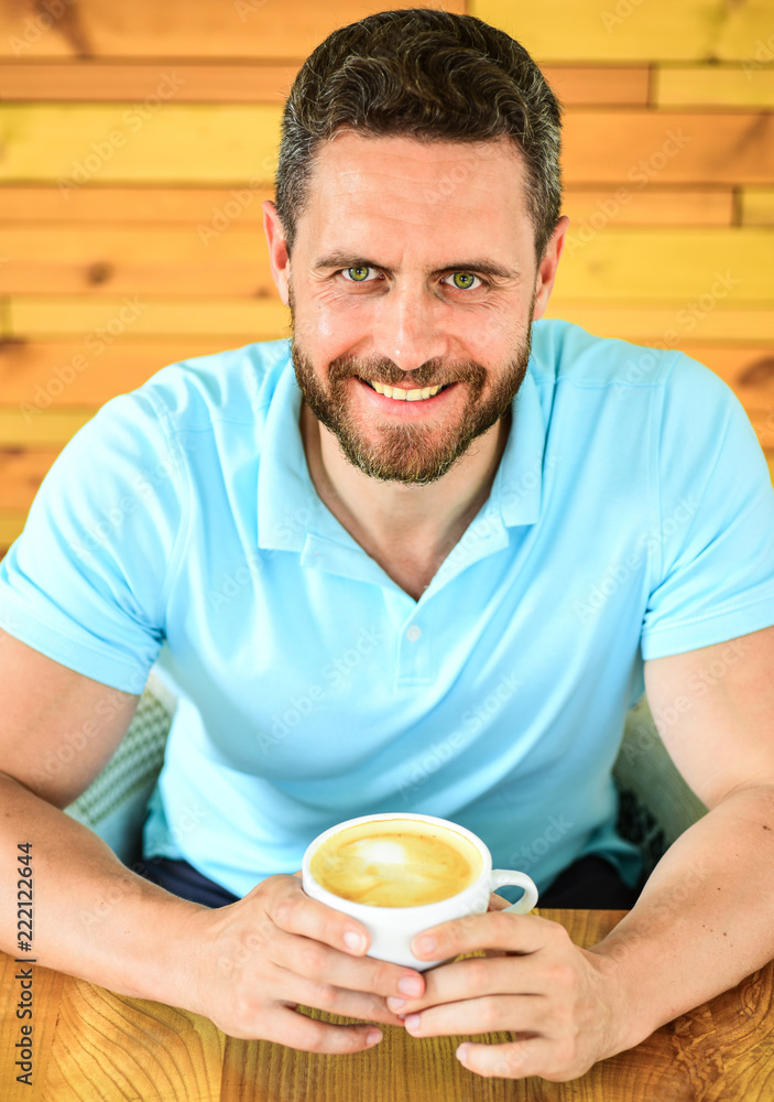 Caffeine can get creative juices flowing when you stuck in rut and it gives you drive. Man bearded guy drinks cappuccino at wooden table cafe. Cafe visitor happy face enjoy coffee caffeine drink Caffeine can get creative juices flowing when you stuck in rut and it gives you drive. Man bearded guy drinks cappuccino at wooden table cafe. Cafe visitor happy face enjoy coffee caffeine drink