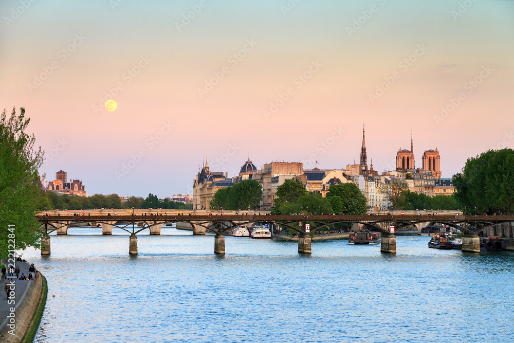 Full moon rise at a pink twilight over the Seine in Paris, France
