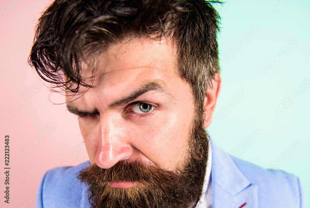 Keep hair tidy and care about hairstyle. Man bearded hipster on strict face  pink blue background.