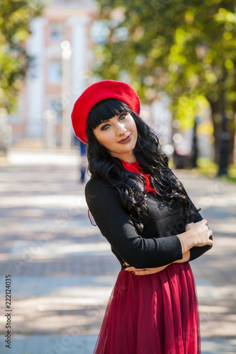 beautiful girl in a red beret and a red skirt for a walk in the city. French style in clothes. Romantic girl
