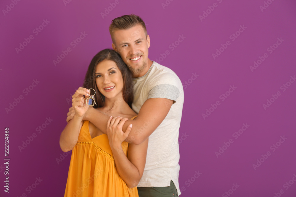 Happy young couple with key from their new house on color background Happy young couple with key from their new house on color background