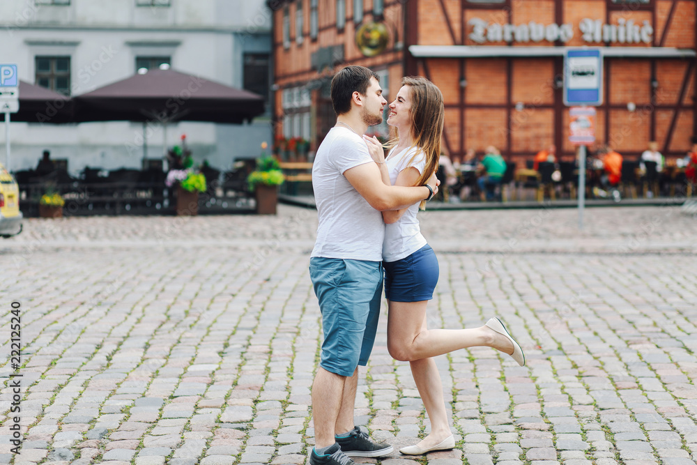 a young couple in shorts and white T-shirts hugging in the city in the summer