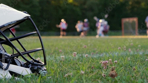 Closeup of lacrosse helmet in the foreground with players and field out of focus in the background. photo