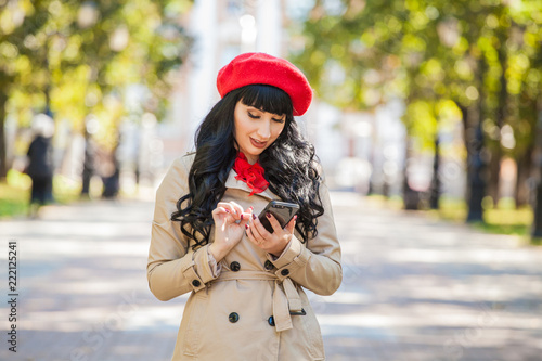 beautiful girl in a red beret and a raincoat talking on the phone,