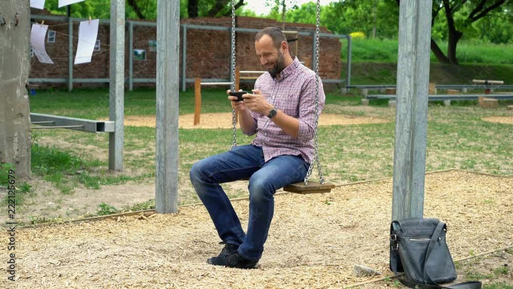 Happy man playing game on smartphone sitting in city park
Happy man playing game on smartphone sitting in city park