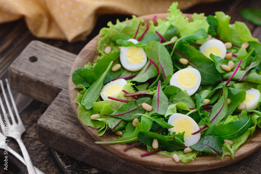 Fototapeta premium Fresh spring appetizing quail eggs, pine nuts, arugula swiss chard salad