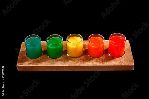 Multicolored opaque cocktails, a set of shots in one row, five servings on a wooden stand, substrate. Side view Isolated black background. Drink for the menu restaurant, bar, cafe photo