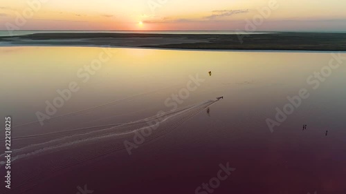 A bright sunset over a pink lake where a man is engaged in kites photo