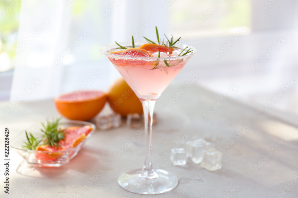 Fresh grapefruit cocktail with rosemary in glass on light table Fresh grapefruit cocktail with rosemary in glass on light table