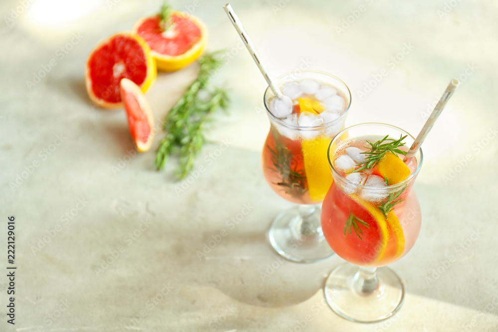 Fresh grapefruit cocktail with rosemary in glasses on light table Fresh grapefruit cocktail with rosemary in glasses on light table