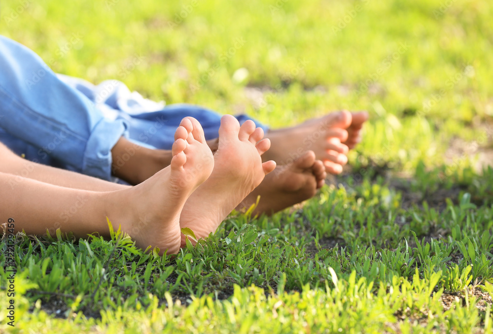 Cute barefoot children lying on grass outdoors Stock Photo | Adobe Stock